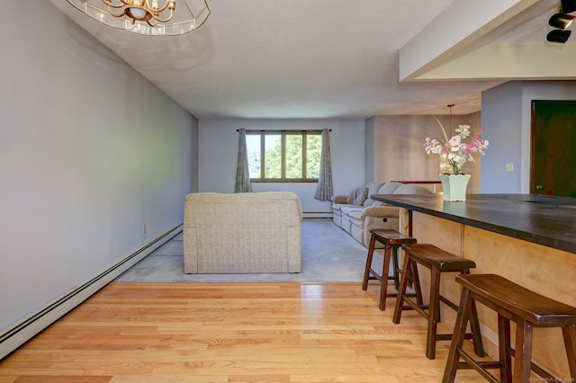 living room featuring a baseboard heating unit, a notable chandelier, baseboard heating, and light wood finished floors