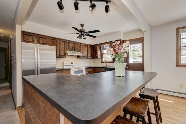kitchen with electric stove, a baseboard heating unit, under cabinet range hood, and dark countertops