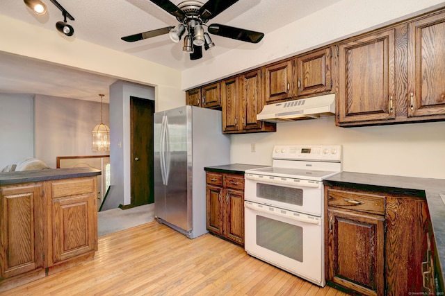 kitchen featuring freestanding refrigerator, dark countertops, under cabinet range hood, and double oven range