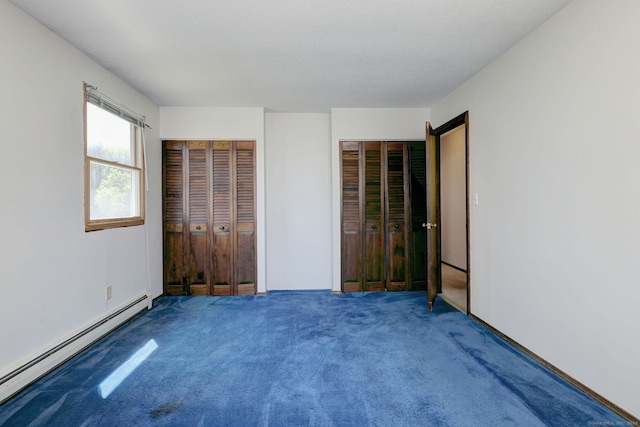 unfurnished bedroom featuring carpet, multiple closets, and a baseboard heating unit