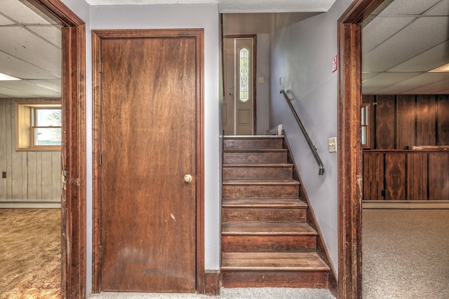 stairway with carpet floors, baseboards, a baseboard heating unit, and a paneled ceiling