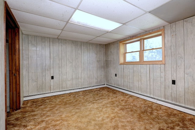 carpeted spare room featuring wood walls and a paneled ceiling
