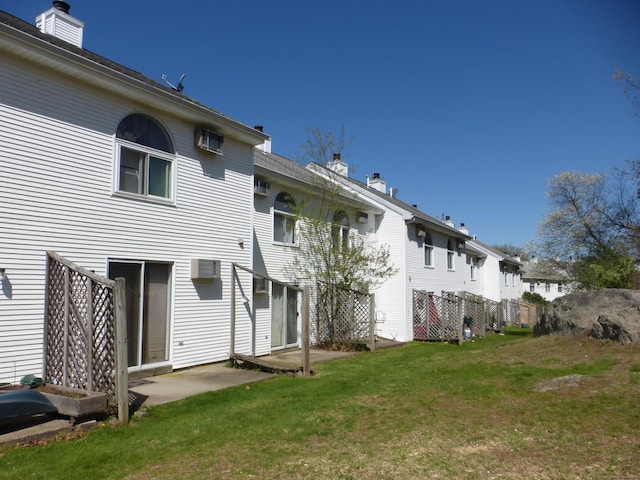 rear view of property with a lawn, a wall mounted air conditioner, and a chimney
