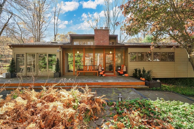 rear view of property featuring a deck and a chimney