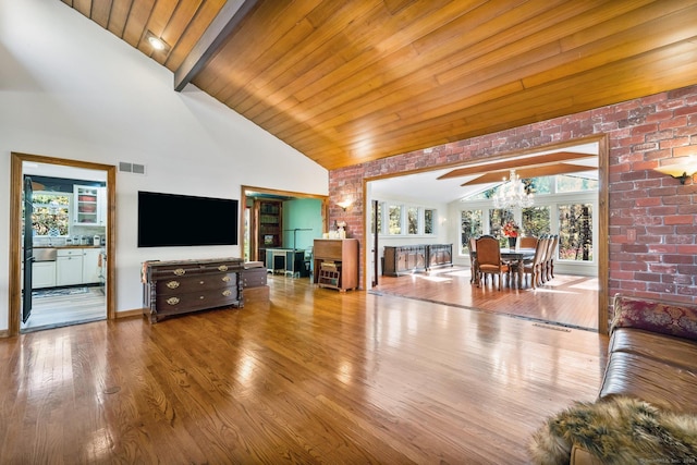 living room with visible vents, an inviting chandelier, beam ceiling, wood finished floors, and high vaulted ceiling