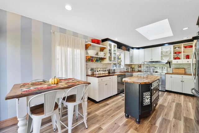 kitchen featuring open shelves, wood counters, appliances with stainless steel finishes, and a skylight