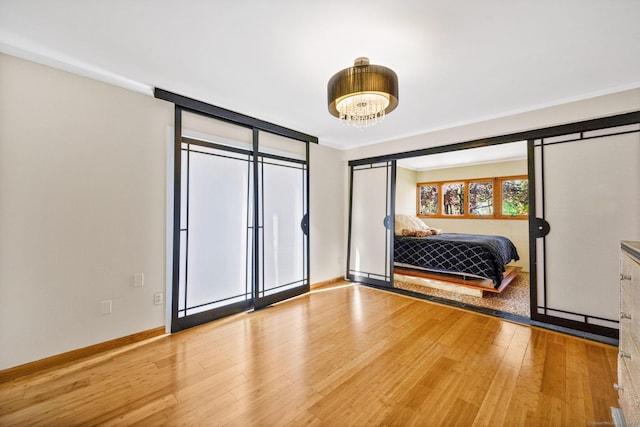 bedroom featuring baseboards, an inviting chandelier, and wood finished floors