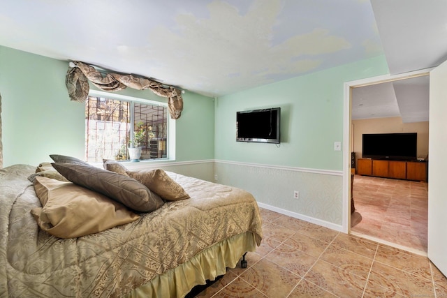 tiled bedroom featuring baseboards and wainscoting