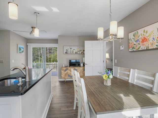 dining space with baseboards, dark wood finished floors, and ceiling fan with notable chandelier