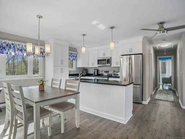 kitchen featuring dark wood-type flooring, white cabinets, dark countertops, and stainless steel appliances