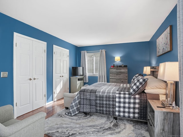 bedroom featuring multiple closets and wood finished floors
