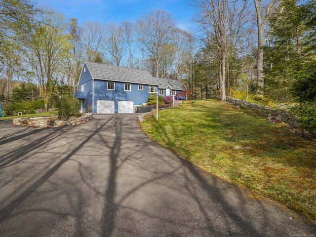 view of front of home with a garage, a shingled roof, a front yard, and aphalt driveway