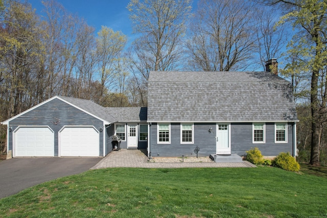 view of front facade with driveway, a chimney, a front lawn, an attached garage, and a shingled roof