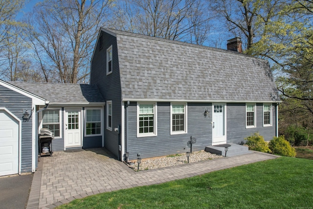 colonial inspired home with roof with shingles, a chimney, and a front lawn