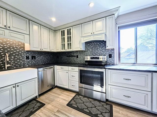 664C Heritage Vlg, Southbury, CT 06488 - kitchen featuring stainless steel appliances, tasteful backsplash, glass insert cabinets, dark countertops, and light wood-style flooring