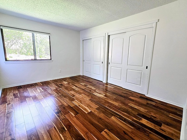 664C Heritage Vlg, Southbury, CT 06488 - unfurnished bedroom with dark wood finished floors, a textured ceiling, multiple closets, and baseboards