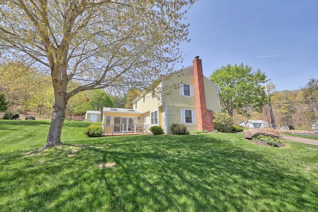 view of side of home with a yard, a deck, and a chimney