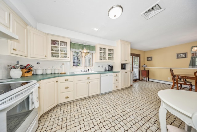 kitchen with visible vents, white appliances, glass insert cabinets, tasteful backsplash, and a sink