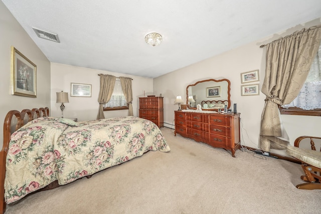 bedroom with light colored carpet, visible vents, and baseboard heating