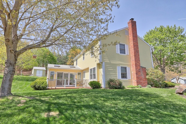 back of house featuring a yard, a deck, and a chimney