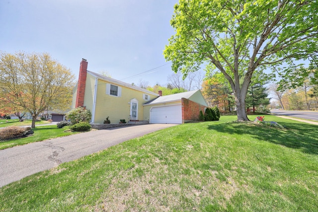 view of side of property with a yard, an attached garage, driveway, and a chimney