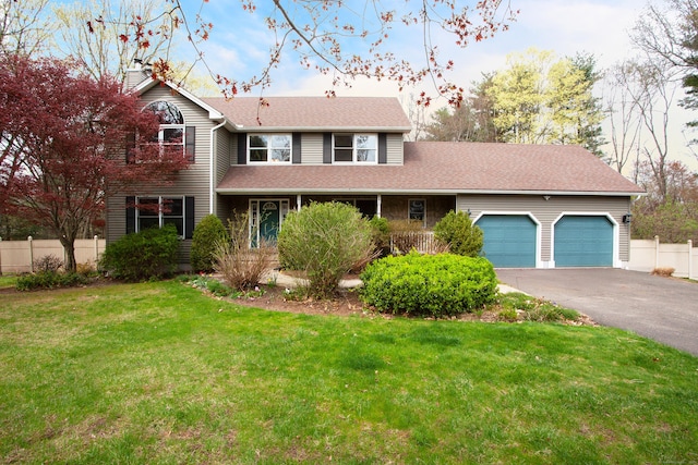 traditional-style house featuring driveway, a balcony, a front yard, fence, and a garage