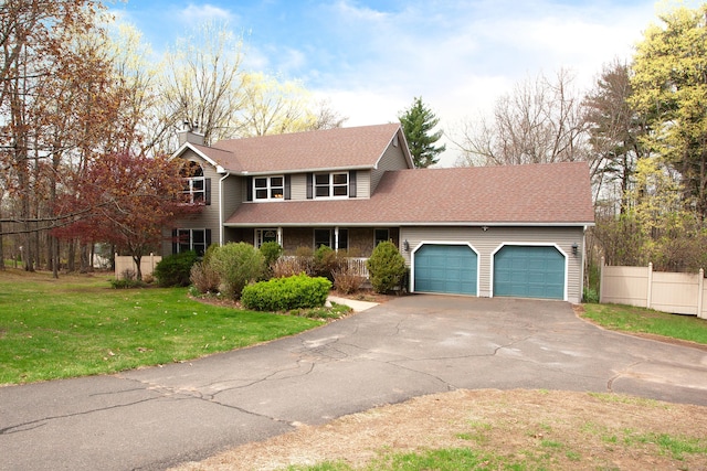 traditional-style house with a front lawn, driveway, a chimney, an attached garage, and fence