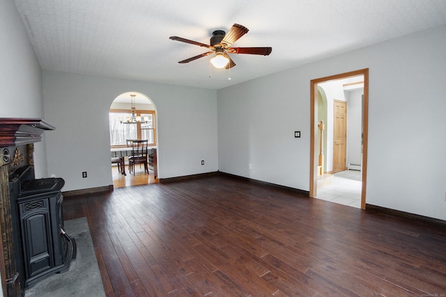 unfurnished living room with wood-type flooring, baseboards, arched walkways, a baseboard radiator, and ceiling fan with notable chandelier