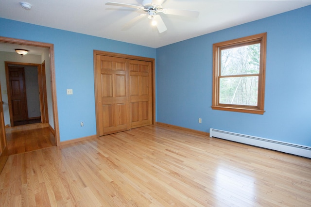 unfurnished bedroom featuring baseboards, baseboard heating, light wood-style floors, and a closet