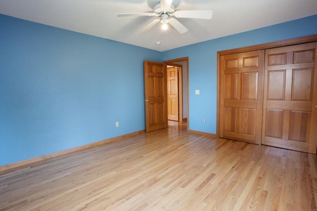 unfurnished bedroom featuring baseboards, a ceiling fan, light wood-style floors, and a closet