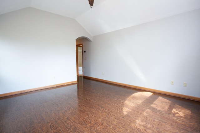 spare room featuring baseboards, arched walkways, wood finished floors, and vaulted ceiling