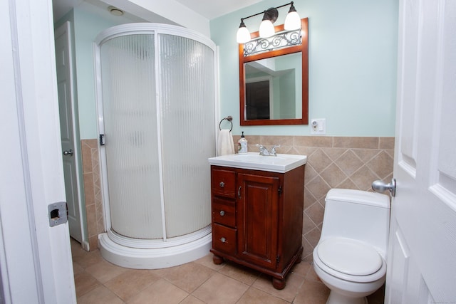bathroom featuring a wainscoted wall, a stall shower, toilet, tile walls, and vanity