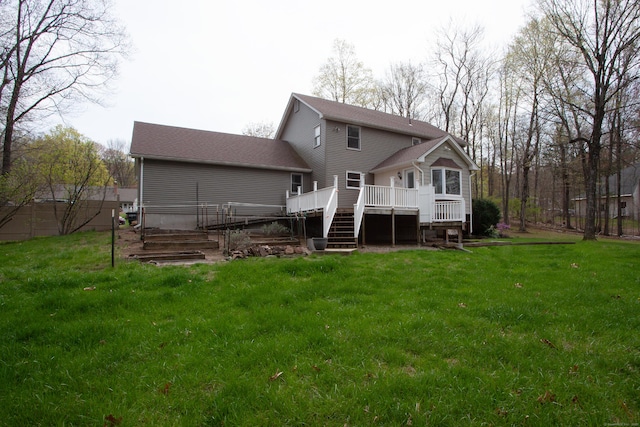 rear view of property featuring a deck, a yard, and stairs
