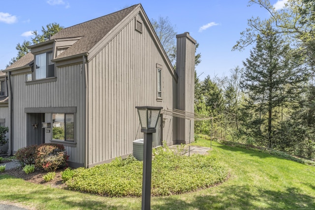 331 Heritage Vlg Unit E, Southbury, CT 06488 - view of side of home featuring roof with shingles, a yard, and central AC unit