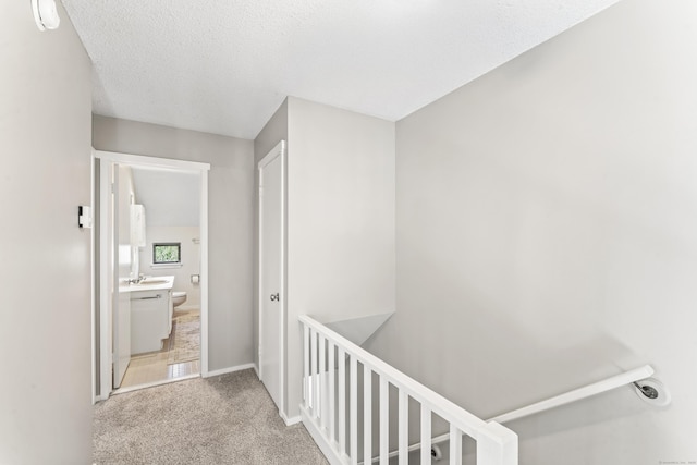 331 Heritage Vlg Unit E, Southbury, CT 06488 - corridor featuring an upstairs landing, carpet floors, a sink, baseboards, and a textured ceiling