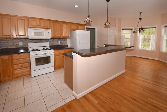 kitchen with dark countertops, white appliances, baseboards, light wood-type flooring, and tasteful backsplash