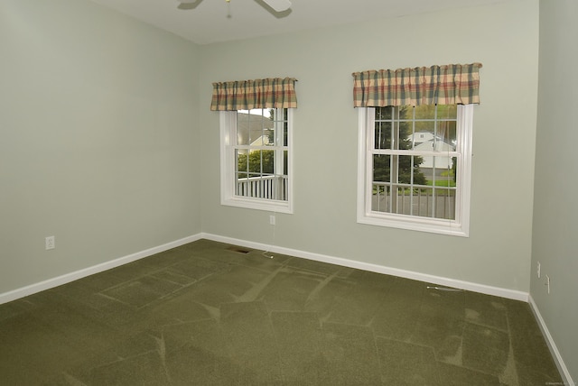 empty room with baseboards, a ceiling fan, dark colored carpet, and visible vents