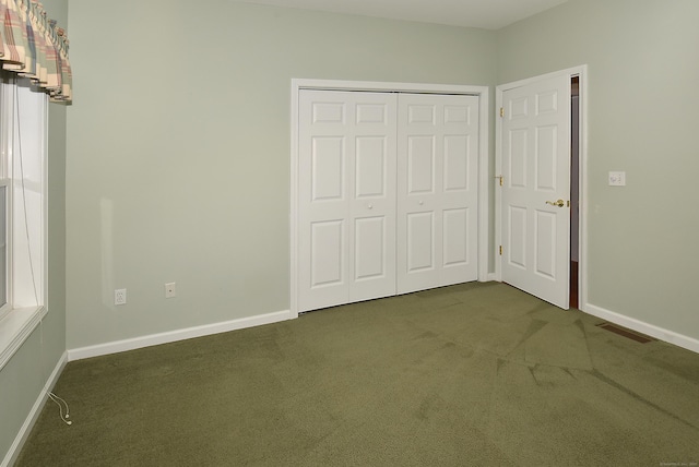 unfurnished bedroom featuring baseboards, dark carpet, and a closet