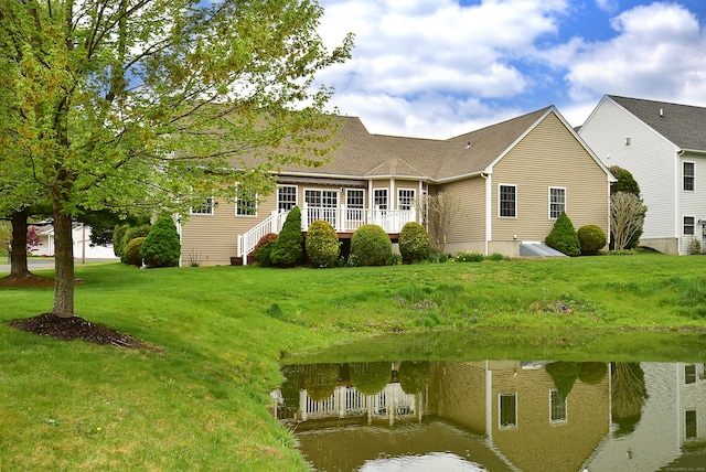 back of house featuring a deck with water view and a yard