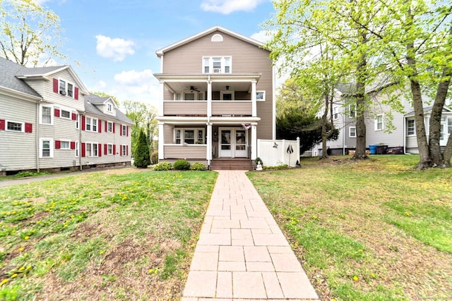 rear view of house with a lawn, ceiling fan, and a balcony