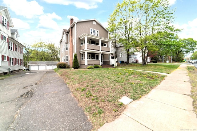 view of front of home with a porch, a chimney, a detached garage, an outdoor structure, and a balcony