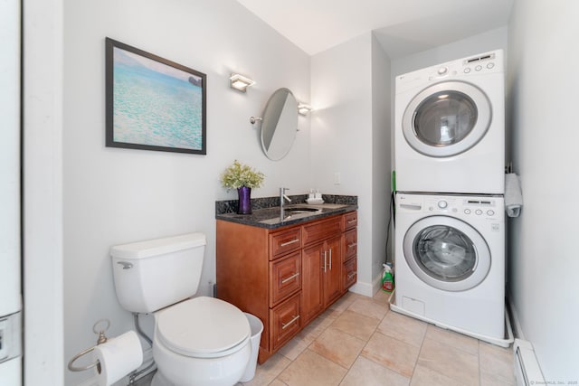 bathroom featuring stacked washer / drying machine, tile patterned flooring, vanity, toilet, and a baseboard radiator