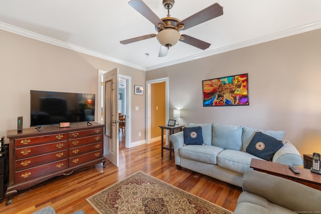 living room featuring baseboards, ornamental molding, a ceiling fan, and wood finished floors