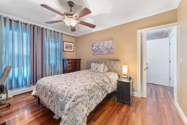 bedroom with crown molding, wood finished floors, and a baseboard radiator
