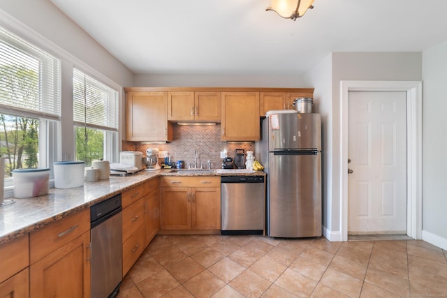 kitchen featuring light stone counters, appliances with stainless steel finishes, a sink, and tasteful backsplash