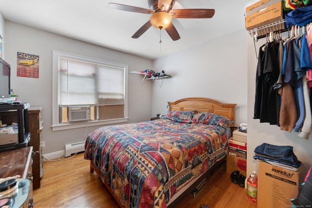 bedroom featuring light wood-style floors, a ceiling fan, a baseboard heating unit, and cooling unit