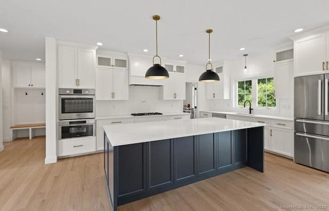 kitchen with a sink, appliances with stainless steel finishes, light wood-style floors, and white cabinetry