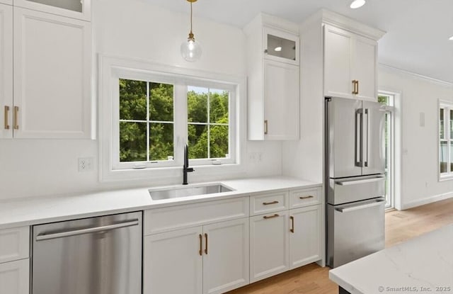 kitchen with glass insert cabinets, light wood-type flooring, white cabinetry, a sink, and stainless steel appliances