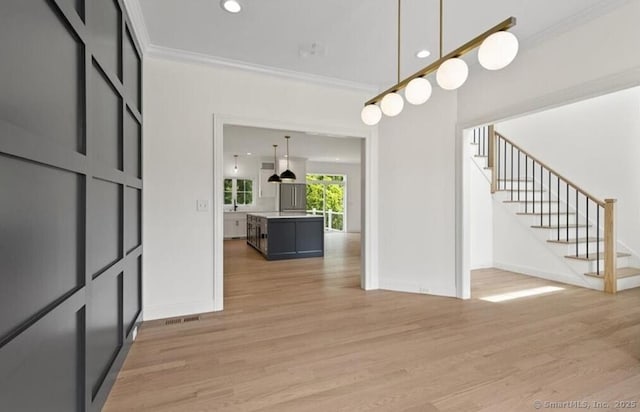 entrance foyer featuring stairway, baseboards, ornamental molding, and light wood finished floors