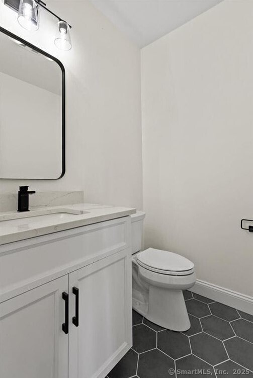 bathroom featuring toilet, tile patterned floors, baseboards, and vanity